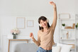 © Pixel-Shot - Smiling young woman in headphones dancing at home