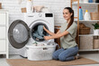 © Pixel-Shot - Beautiful young happy woman with basket taking clean laundry from washing machine at home