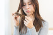 © KMPZZZ - Damaged Hair, frustrated asian young woman, girl hand in holding splitting ends, messy unbrushed dry hair with face upset, long disheveled hair, health care of beauty. Portrait isolated on background