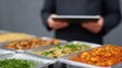 © Business Image - Professionelles Catering im deutschen Büro, bei dem die Mitarbeiter die Nährwertangaben auf einem Tablet verwalten.