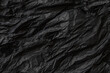 © Ole - Texture of crumpled black paper with many folds and creases for background and overlay. The lighting show details in the material