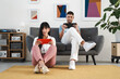 © Studio Marmellata - A young couple enjoys playing video games together in a modern living room, one on the couch and the other on the floor.