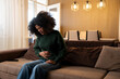© Nenad - Young woman experiencing abdominal pain holding stomach in discomfort sitting on sofa at home