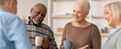© Prostock-studio - Four friends enjoy a conversation while drinking coffee. They stand close together, smiling and engaged in a light-hearted discussion. The setting is bright and welcoming.