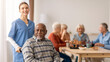 © Prostock-studio - A caregiver assists an elderly man in a senior care center. Other residents play chess and socialize at tables. The space is bright with large windows. Various activities are happening.