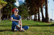 © SHOTPRIME STUDIO - Lifestyle woman in modern boho-western denim street style sitting on grass outdoors, wearing sunglasses with film color effect, relaxed and smiling in sunny park environment.