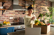 © Davor - Smiling woman unboxing fresh groceries in home kitchen