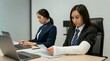 © Evarelle - Asian woman with arm in cast working in office. Injured employee reading document at desk with laptop. Professional recovery, workplace safety, disability inclusion and career concept.