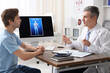 © New Africa - Man having appointment with urologist at wooden table in clinic