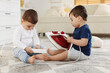 © New Africa - Child safety at home. Little twin brothers playing with electric devices on floor indoors