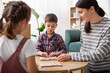 © New Africa - Smiling mother and her children playing with educational toys at wooden table indoors
