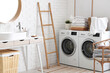 © Pixel-Shot - Interior of laundry room with washing machines, ladder and clean bed sheets