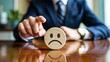 © Awais Haider - Businessman holding sad emotion icon representing customer dissatisfaction feedback and service rating concept