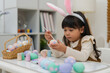 © geargodz - preschool child girl wearing bunny ears painting and decorating colorful egg at home on easter day
