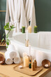 © Pixel-Shot - Burning candles with towels and cosmetic products on table near bathtub in bathroom