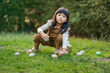 © geargodz - child girl playing and hunting for Easter eggs into a basket on green grass in garden