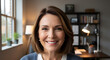 © Aura - A professional mature woman smiling at the camera during a virtual meeting in a home office