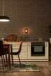 © Pixel-Shot - Interior of kitchen with glowing lamps, white counters, dining table and chairs at evening