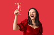 © Pixel-Shot - Happy young woman holding glass of tasty cocktail with strawberry on red background