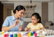 © Anaya - Woman and child painting easter eggs on a white table