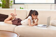 © Blue Jean Images - Girl lying on sofa, using laptop