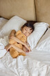 © Blue Jean Images - A girl sleeping in bed with a toy bear in her arms