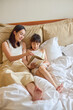 © Blue Jean Images - Mum and daughter lying on bed, reading books
