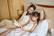 © Blue Jean Images - Mum and daughter lying on bed, reading books