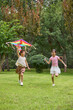 © Blue Jean Images - Two girls fly a kite in the park