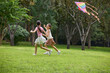 © Blue Jean Images - Two girls fly a kite in the park