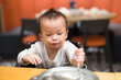 © leungchopan - Little baby playing with utensils at restaurant