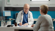 © DC Studio - Male doctor using recovery medication to give prescription paper to retired patient in medical office. Writing information to give treatment for illness diagnosis, health care system.