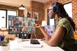 © DC Studio - Black female manager uses headphones and computer in communicating with colleagues during virtual meeting. Self employed woman virtually presenting startup project with potential clients on video call