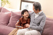 © Blue Jean Images - Grandpa and grandson sharing a phone on the couch