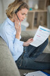 © auremar - woman looking at paperwork at talking on wireless headset