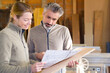 © auremar - male and female carpenters looking plans in workshop