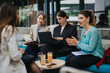 © qunica.com - Four businesswomen collaborating over a laptop and notes in a modern lounge setting. The group discusses ideas and reviews documents during an informal meeting.