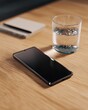 © misunderst00d - Modern smartphone, water glass, and notepad with pen on natural wood desk, suggesting work, study, or daily routine