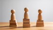 © Riley - Three wooden human figures standing on stacked blocks,leadership hierarchy and team structure concept,organizational ranking and business management strategy visualization