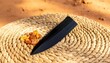 © Damirstudio - A sleek black obsidian blade rests on a woven rush mat beside amber crystals, evoking ancient tools and natural artistry.