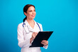 © deagreez - Cheerful female doctor with clipboard and stethoscope preparing for checkup in a bright blue studio promoting healthcare and professional medical care