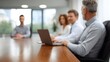 © Bussakon - Business people in a modern conference room collaborating around a table with a laptop