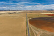 © Austockphoto - Aerial view of ploughed circular paddock alongside a country road under a blue sky