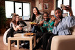 © DC Studio - Distinct ethnicities happy people eating snacks, drinking wine, posing for smartphone selfie. African american woman taking selfie with friends at apartment birthday party.