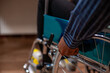 © DC Studio - Closeup on hands of african american person spinning wheel of his wheelchair and entering his workplace. Black businessman with disability seated at wheelchair friendly office desk.