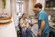 © PintoArt - Caregiver assisting disabled woman in home kitchen