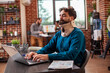 © DC Studio - Professional male analyst evaluating research data on a digital device and handling work responsibilities during recovery. Bearded man with a neck brace uses a laptop in a brick-wall office.