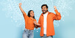 © Prostock-studio - Two individuals are smiling and showing excitement. They are wearing orange shirts and standing against a light blue background with a decorative design.