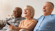 © Prostock-studio - Three friends sit on a couch, laughing and enjoying their time together while watching a TV show at home. The scene shows their happiness and connection as they spend quality time.