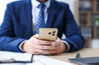 © New Africa - Man using modern smartphone at wooden desk in office, closeup